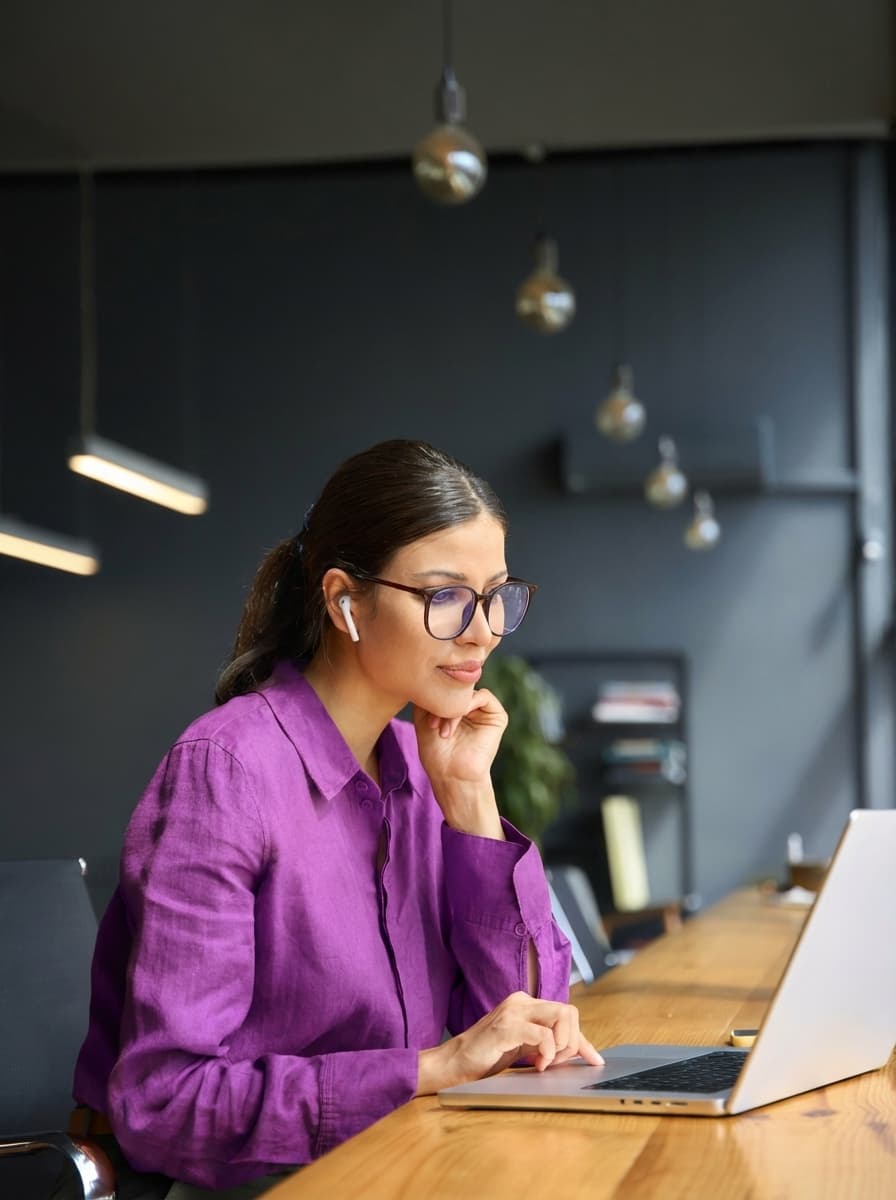 Mujer joven tranquila trabajando con un portátil en un salón luminoso y minimalista